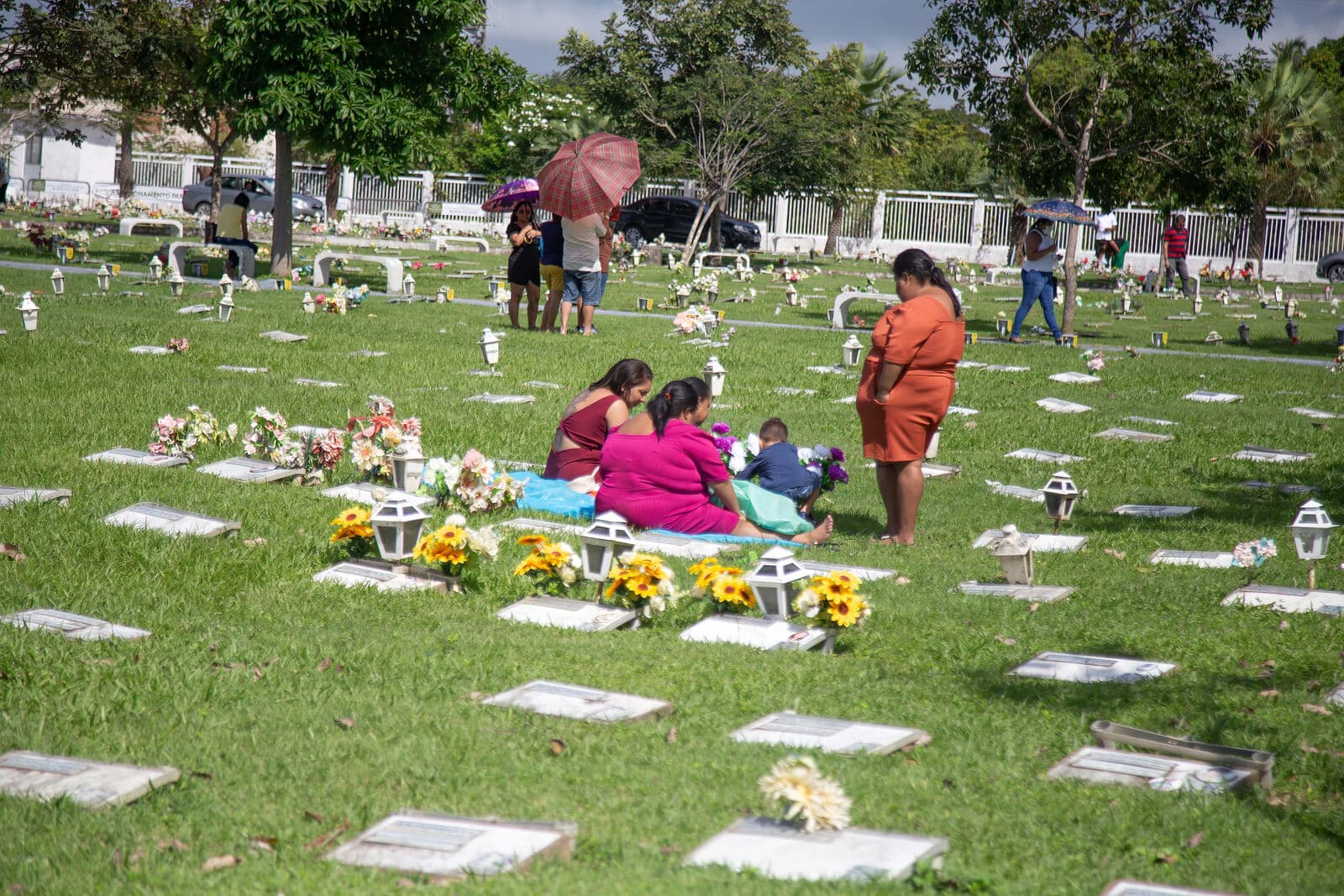 Famílias visitando e enfeitando túmulos no Dia das Mães