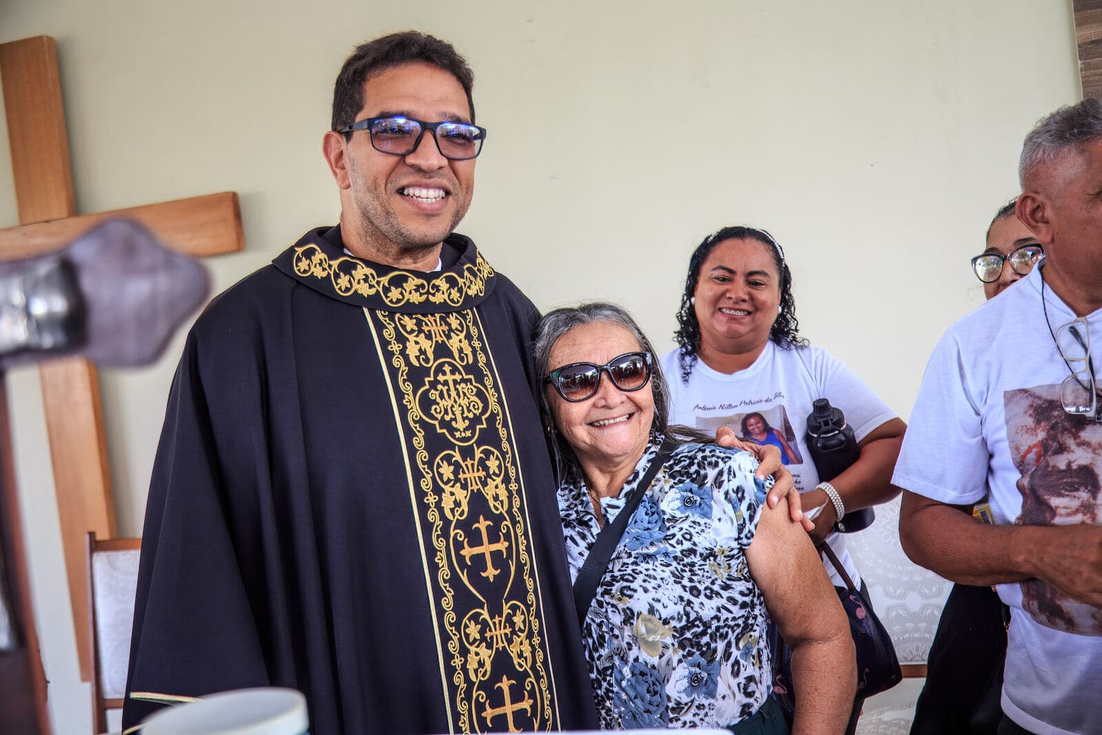 Padre com uma família durante a celebração de Finados